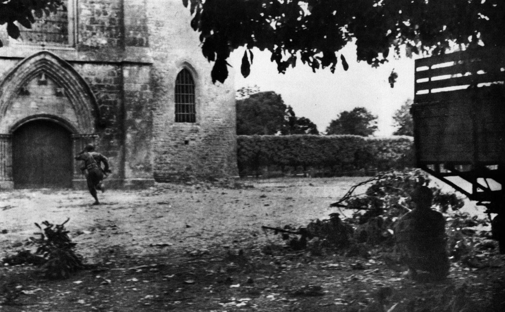 Troopers of the 505th PIR run for the door of the church in Sainte-Mère-Église as German artillery lands in the town on June 6, 1944.