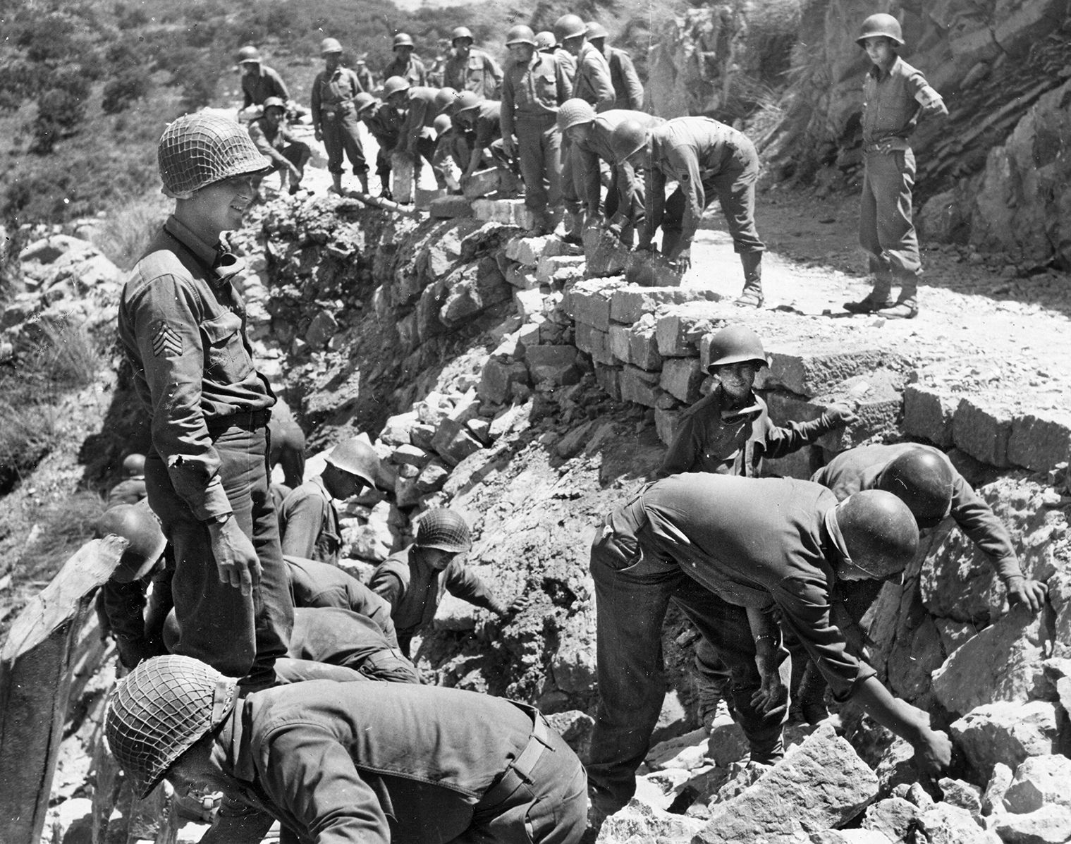 The Germans tried to slow the American advance from Palermo to Messia along the rugged northern coast of the island by destroying the roads. Here, American combat engineers work to repair the damage so the drive could continue.