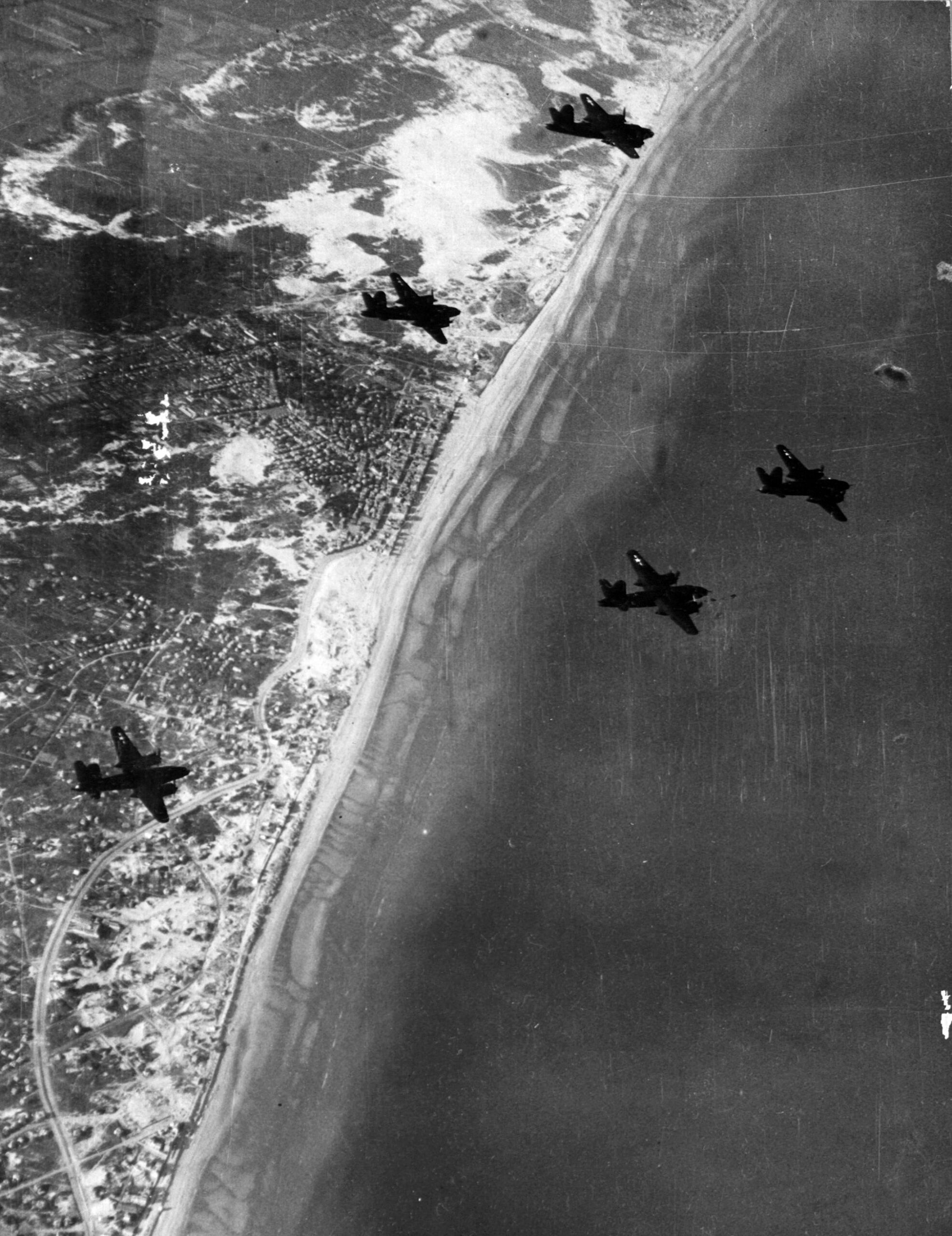 A flight of B-26s leave Dutch airspace after a raid. Note puff of smoke (upper right) from an exploding flak shell. 