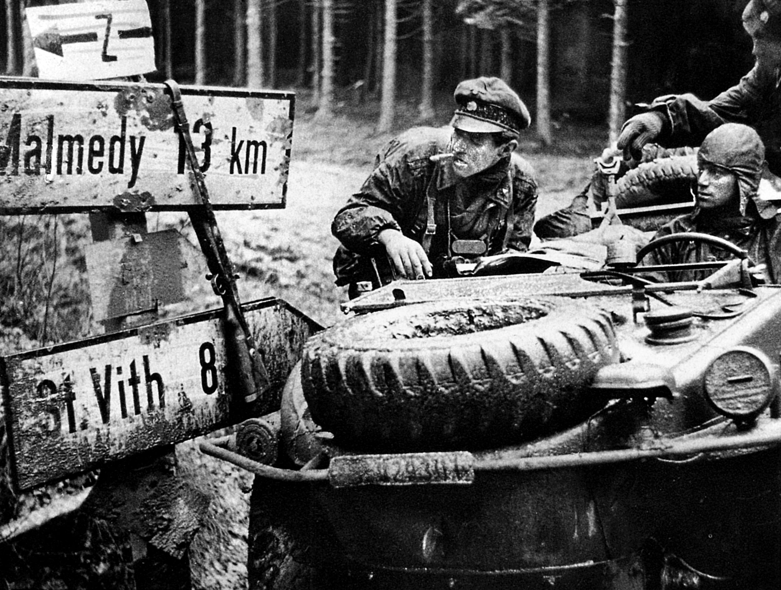 Men of Kampfgruppe Peiper pause to consult a map and road signs during the opening hours of the unit’s attack. The officer has often been misidentified as Peiper in this captured war photo. 