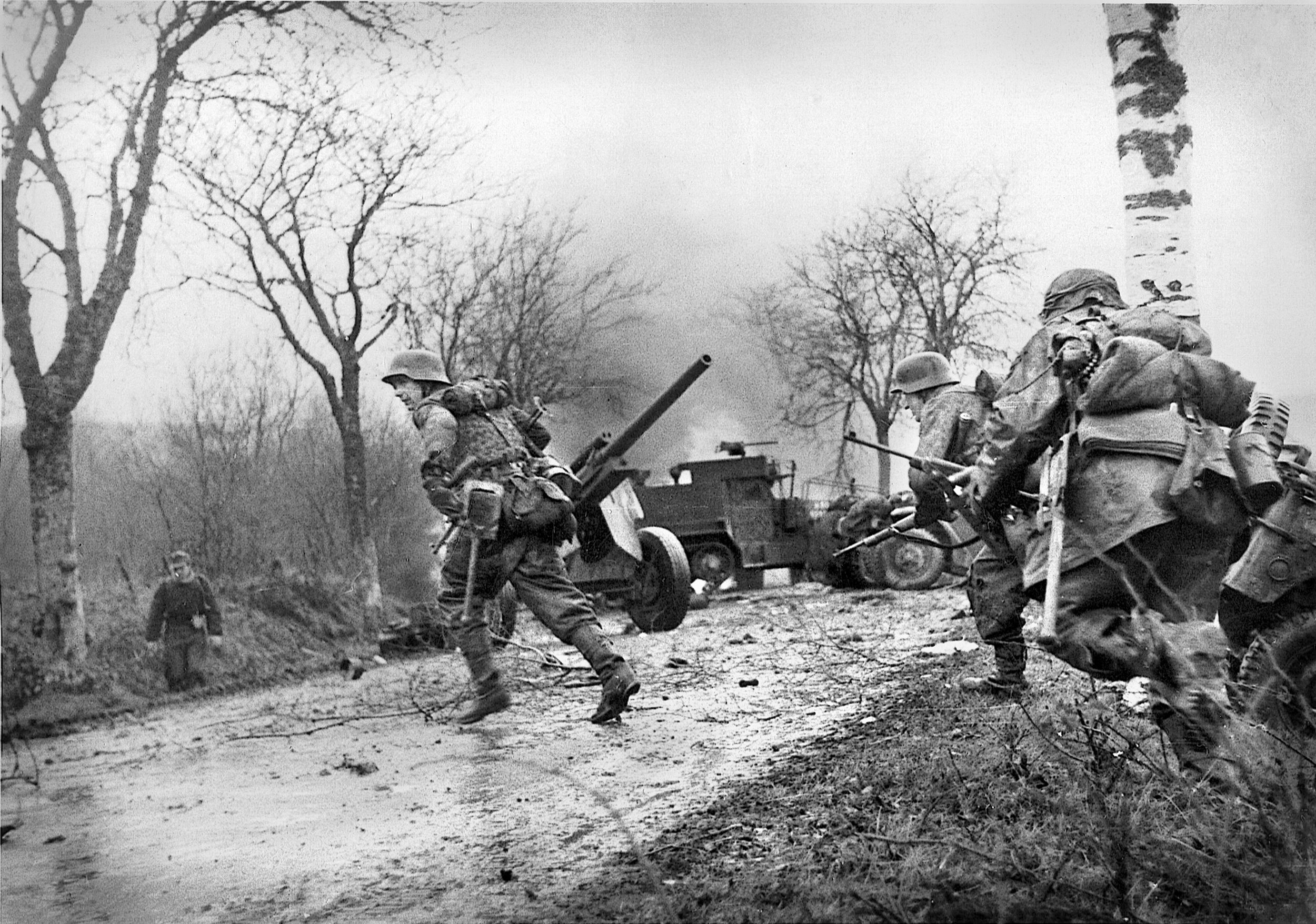 German soldiers dash across a Belgian road, reenacting their attack for German cameramen after ambushing an American convoy in the first days of the Ardennes offensive. Peiper’s men had several encounters with U.S. units while on their drive to the Meuse River.