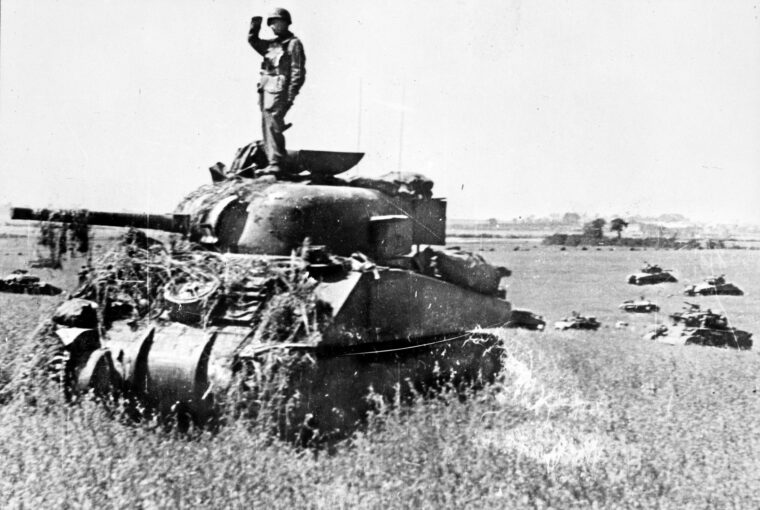 Once out of hedgerow country, Sherman tanks of the 10th Armoured Cavalry Brigade roll in support of the 2nd Canadian Division during Operation Tractable.
