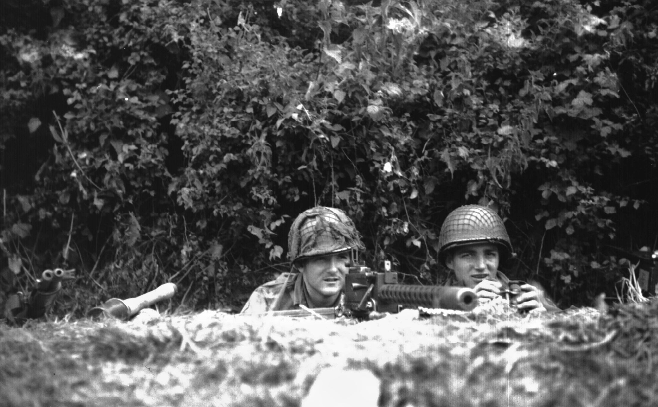 From their position in a hedgerow, .30-caliber machine gunners Walter “Smokey” Gordon (left) and Frank Millett, 506th PIR, stay alert for approaching Germans.