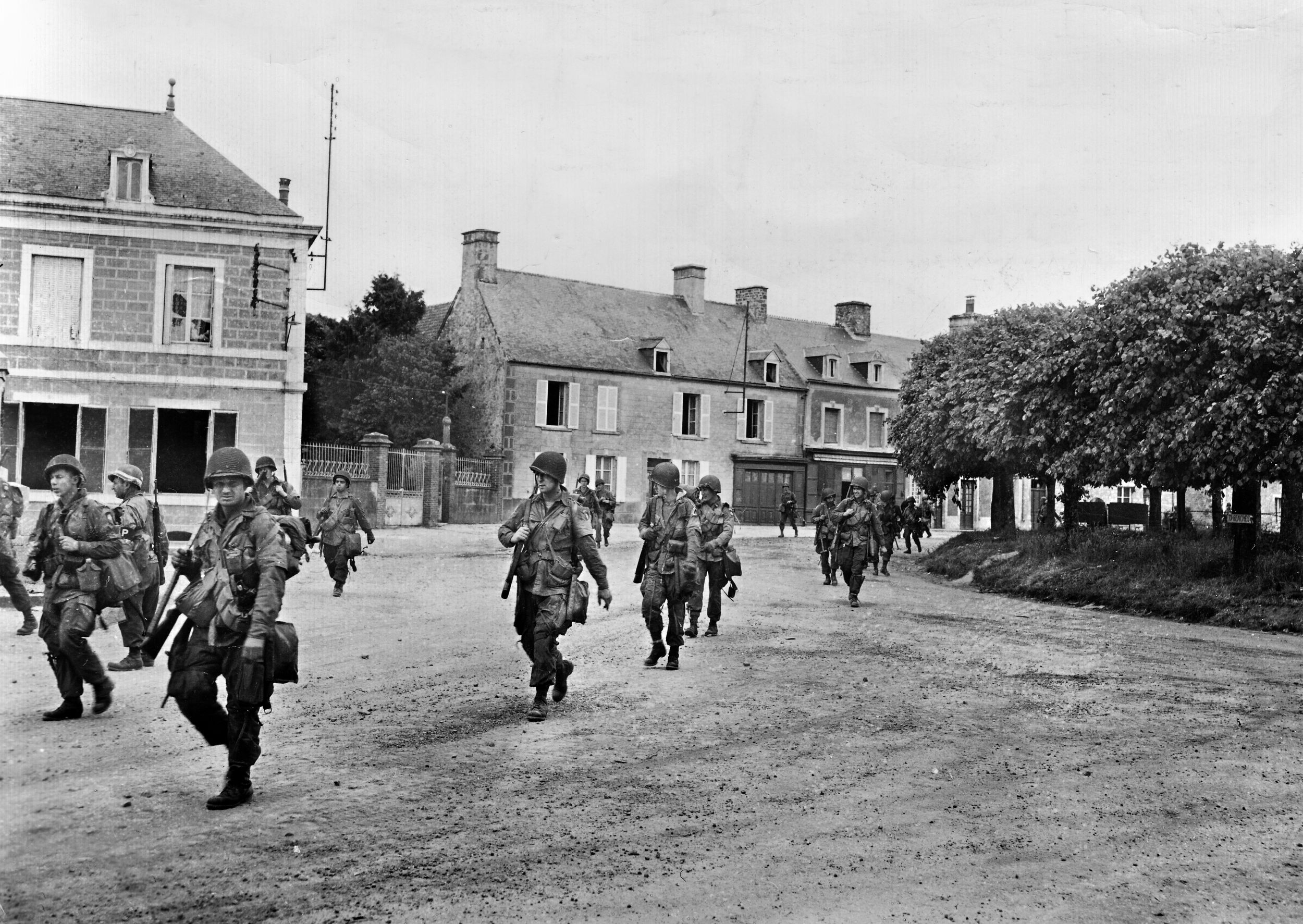 Like American tourists on a sight-seeing trip, members of the 101st Airborne Division casually walk through Sainte-Marie-du-Mont on their way to engage in battle Carentan.