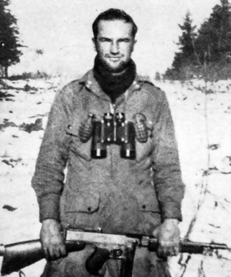  Six months after D-Day, Lieutenant Speirs, now CO of Company E, 506th PIR, poses for a photo in snowy Bastogne wearing his jump jacket, two grenades, and holding a Thompson sub-machine gun.