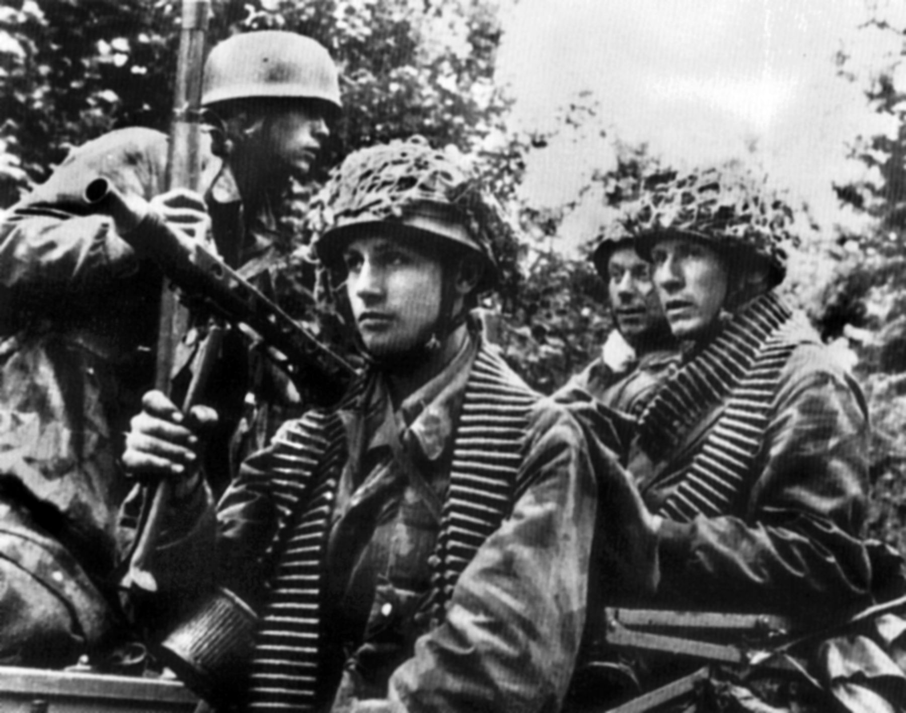 With belts of 7.92mm ammunition around their necks, this MG42 team from von der Heydte’s 6th Fallschirmjager Regiment prepares to move out against 506th PIR units that have dropped into the area. 
