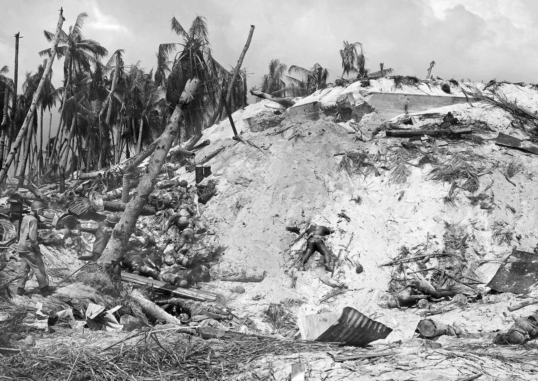 Once the island was secured, a Marine (left) walks through a grim landscape littered with burned and bloated Japanese corpses.