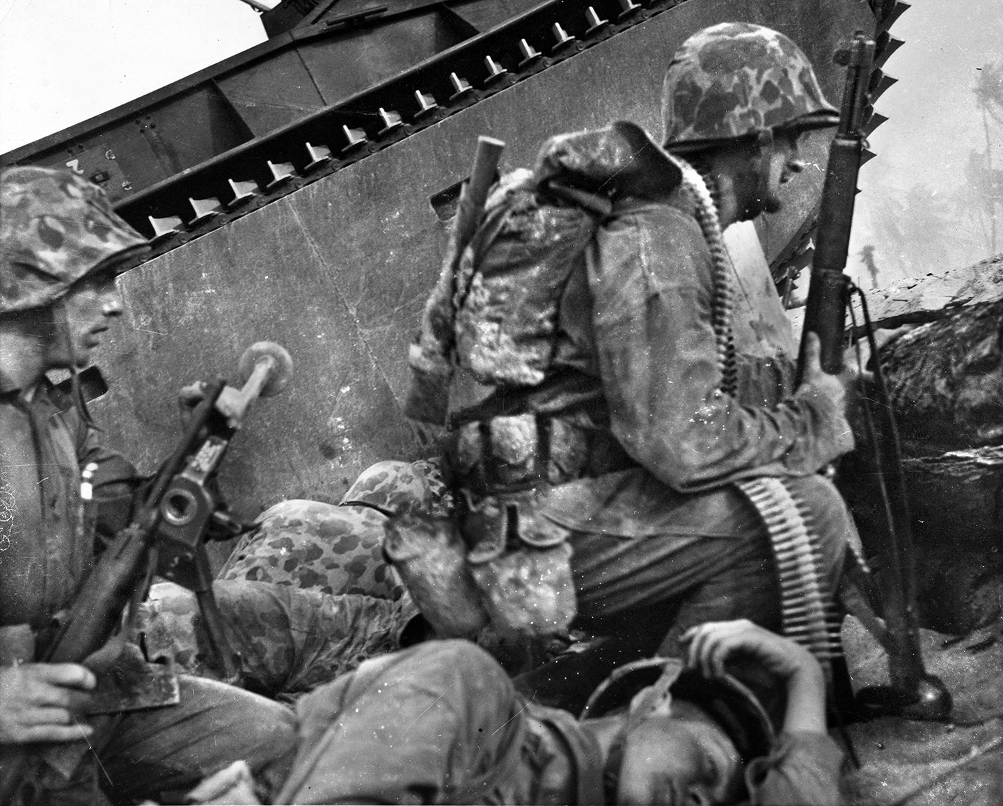 A Marine lies dead (foreground) as a machine-gun team, taking cover beside an LVT amphibious tractor (also called amtracs), prepares to advance toward the airfield. 