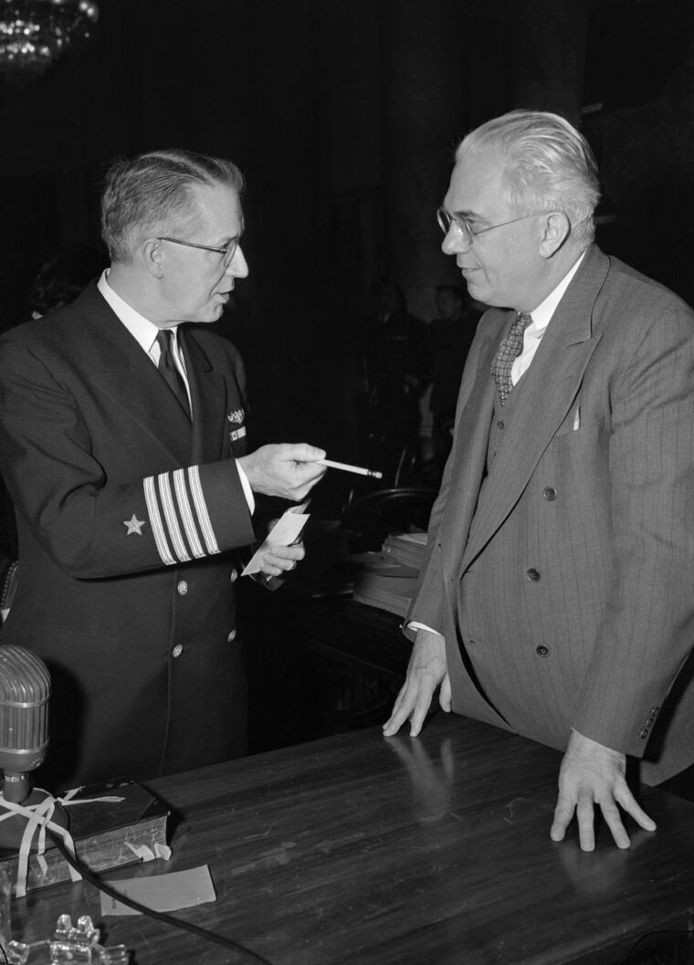Captain L.F. Safford, chief of the Naval Intelligence section during the time of Pearl Harbor and a hearing witness, confers with Senator Homer Ferguson after a session.