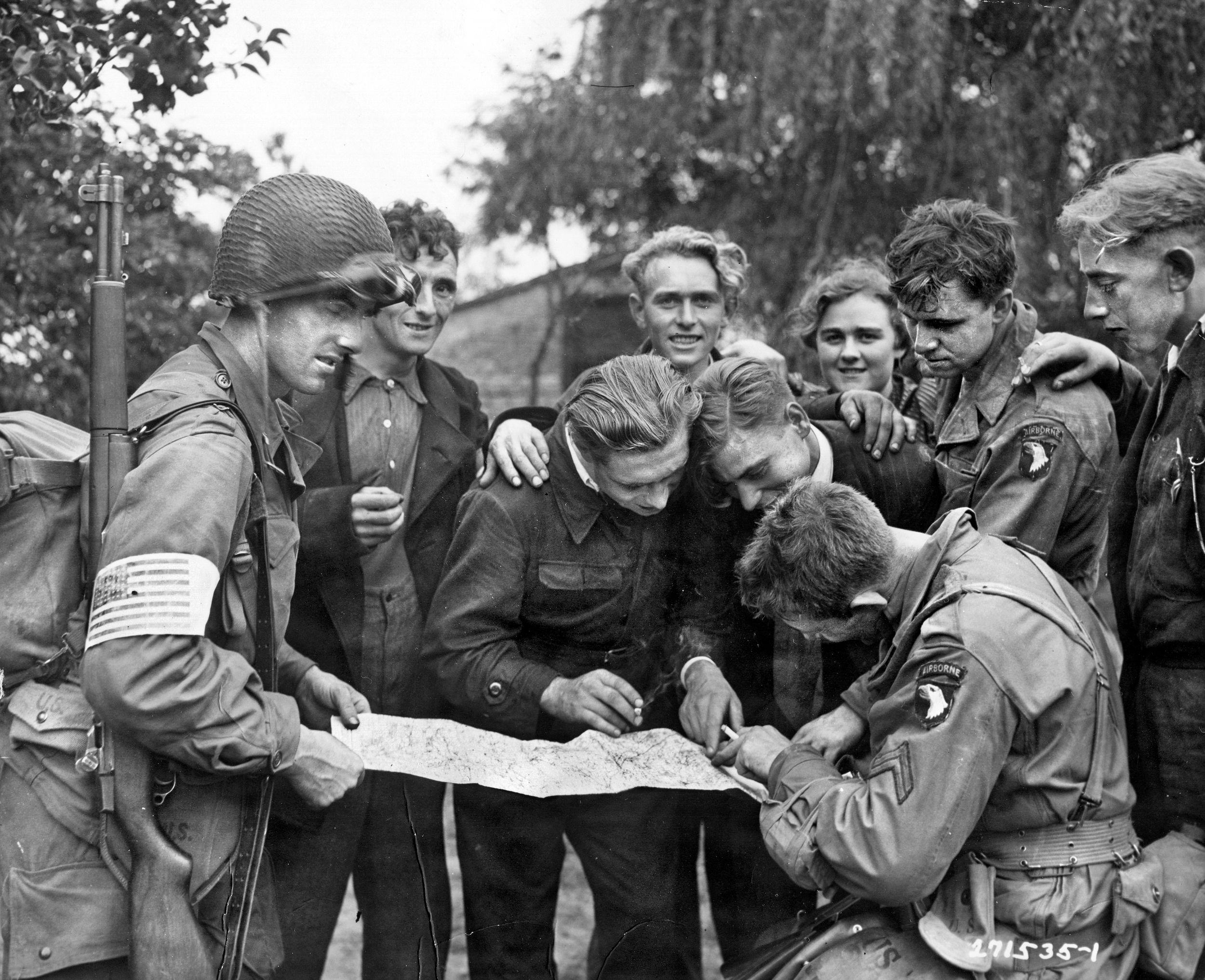 Dutch civilians, identified by some sources as members of the resistance, talk with troopers of the American 101st Airborne Division as they look over a map of the area.