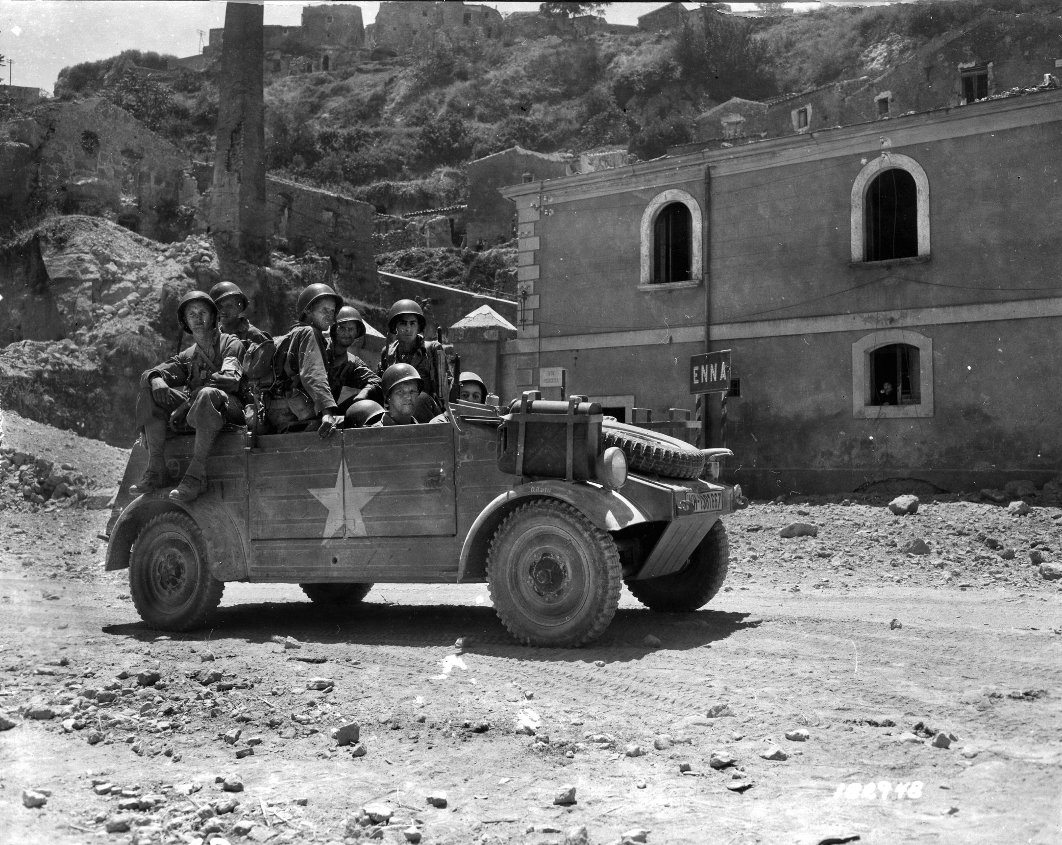 After taking the town of Enna, Sicily, on July 20, 1943, American soldiers of Company I, 1st Infantry Division ride through the town in a captured German vehicle that has been emblazoned with the U.S. star insignia. 