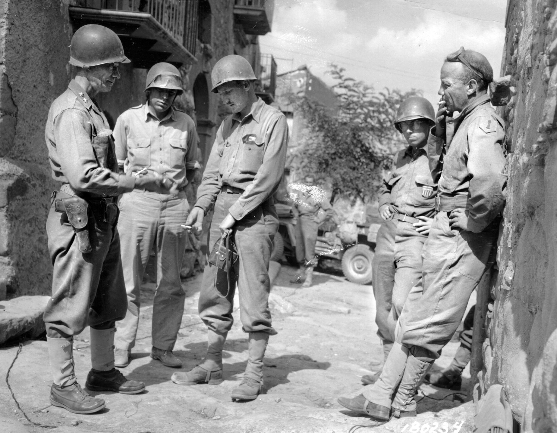 Major General Terry Allen, commander of the U.S. 1st Infantry Division, stands at left and confers with Brigadier General Ted Roosevelt, far right, along with war correspondents as the tactical situation in Sicily develops in August 1943.