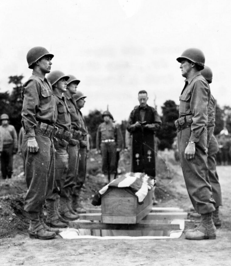 General Ted Roosevelt died of a heart attack during the Normandy Campaign. He was buried with full military honors in Normandy, and in this photo of his funeral soldiers stand at attention beside his flag draped coffin.