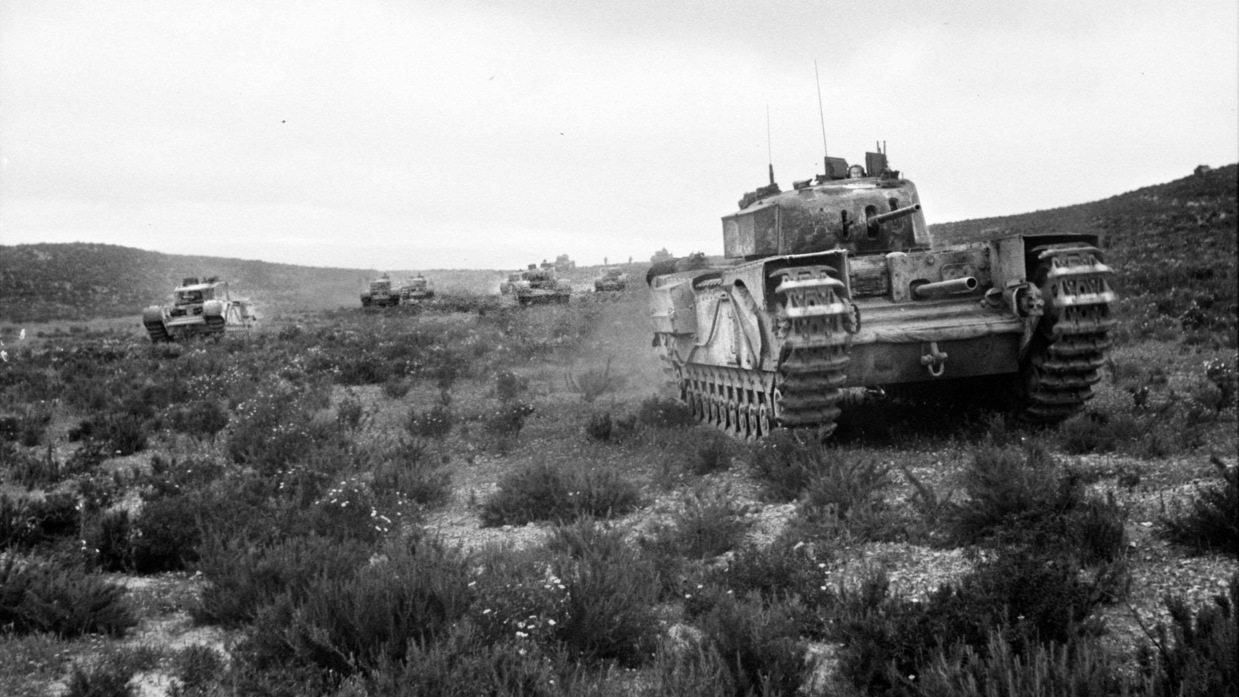 A German PzKpfw. III tank accompanied by infantry advances across difficult terrain in Tunisia. Hollands, joined by a second Churchill, knocked out two PzKpfw. III tanks during the fight.
