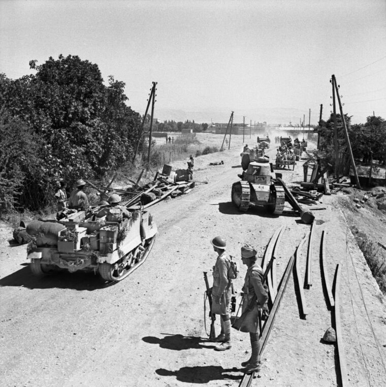 A Bren gun carrier manned by Indian troops heads toward Damascus. A disabled Vichy FT-17 tank lies on the right side of the road. 