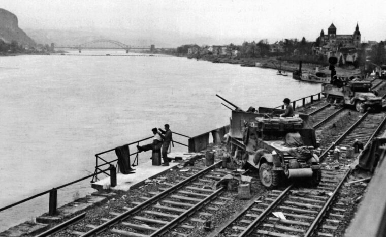 Half-track-mounted antiaircraft guns stand guard on a partially demolished bridge downstream on March 17. The Ludendorff Bridge, visible in the distance, collapsed that day after being weakened by aerial assaults, artillery barrages, and V-2 rocket attacks.