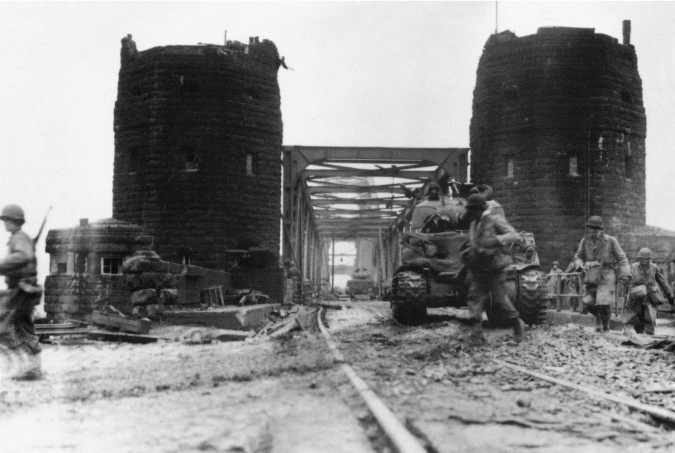 After its capture, First Army pushes troops over the bridge to establish a bridgehead on the eastern bank of the river. Here infantrymen and M4 tanks move across on March 11.
