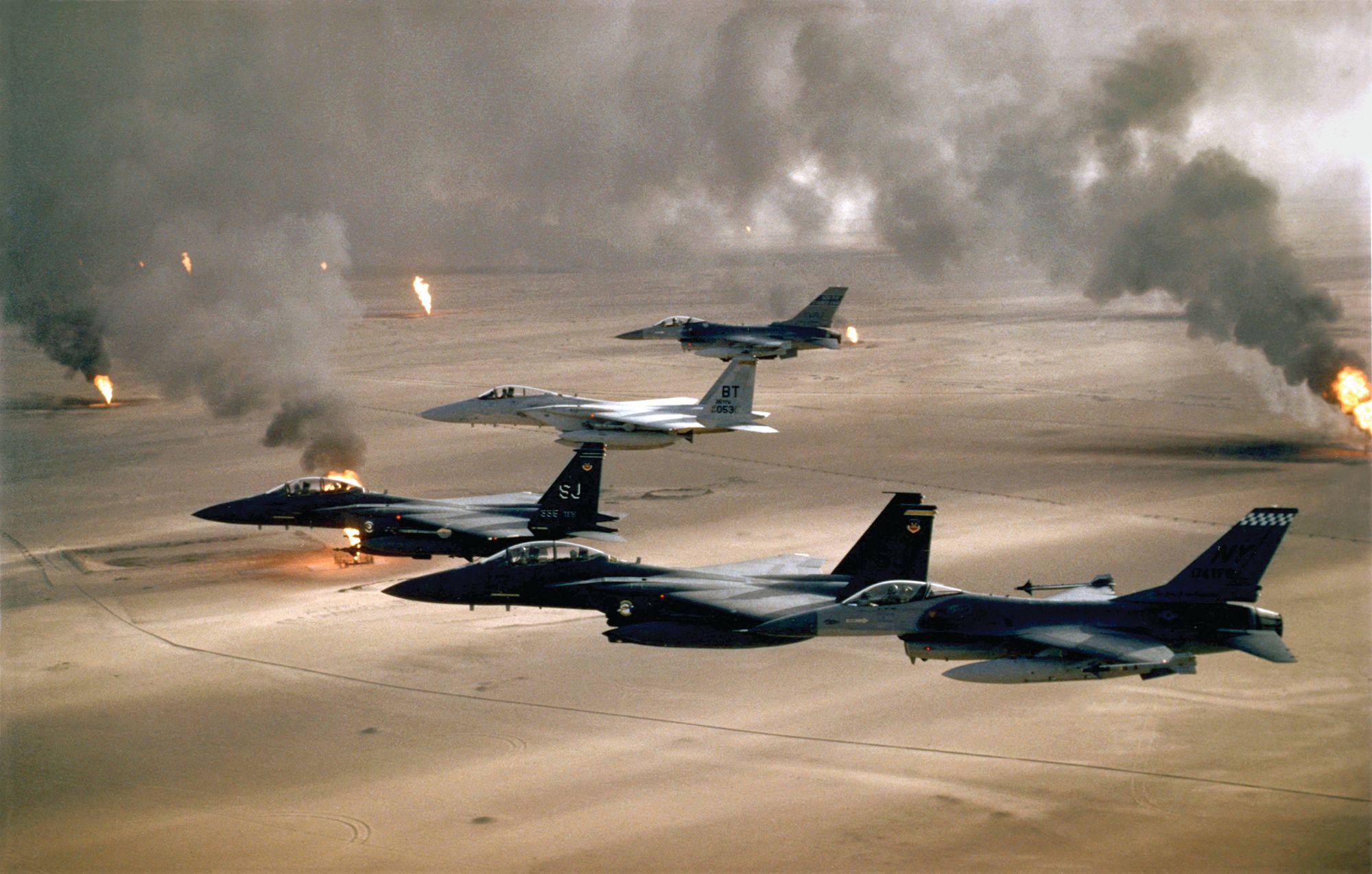U.S. Air Force fighter aircraft fly through a thick screen of smoke caused by burning oil wells that coincided with the Coalition's air strikes. Several F-15 pilots shot down Iraqi aircraft on the first night of the war, while F-16 pilots participated in deep-penetration strikes against command-and-control bunkers, SCUD targets, and airfields.