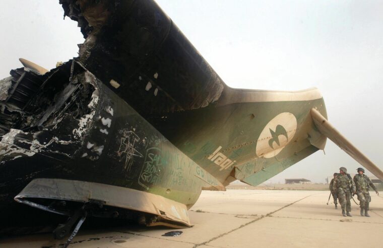Combat engineers walk past a destroyed Iraqi plane at Baghdad International Airport. When Sergeant Smith spotted a large force of Iraqi soldiers in a trench near his position, he requested reinforcements and led an assault against the Iraqis. 