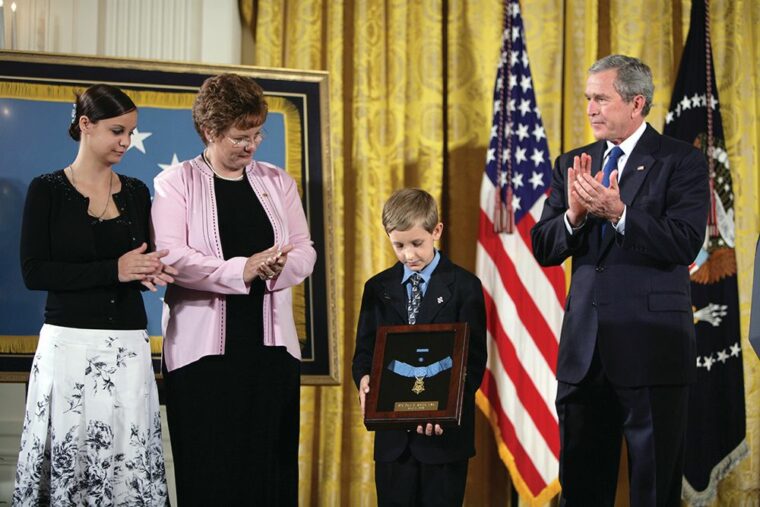 Sergeant Smith's son, David, holds his father’s Medal of Honor after President George W. Bush presented it to the family in a White House ceremony in April 2005.