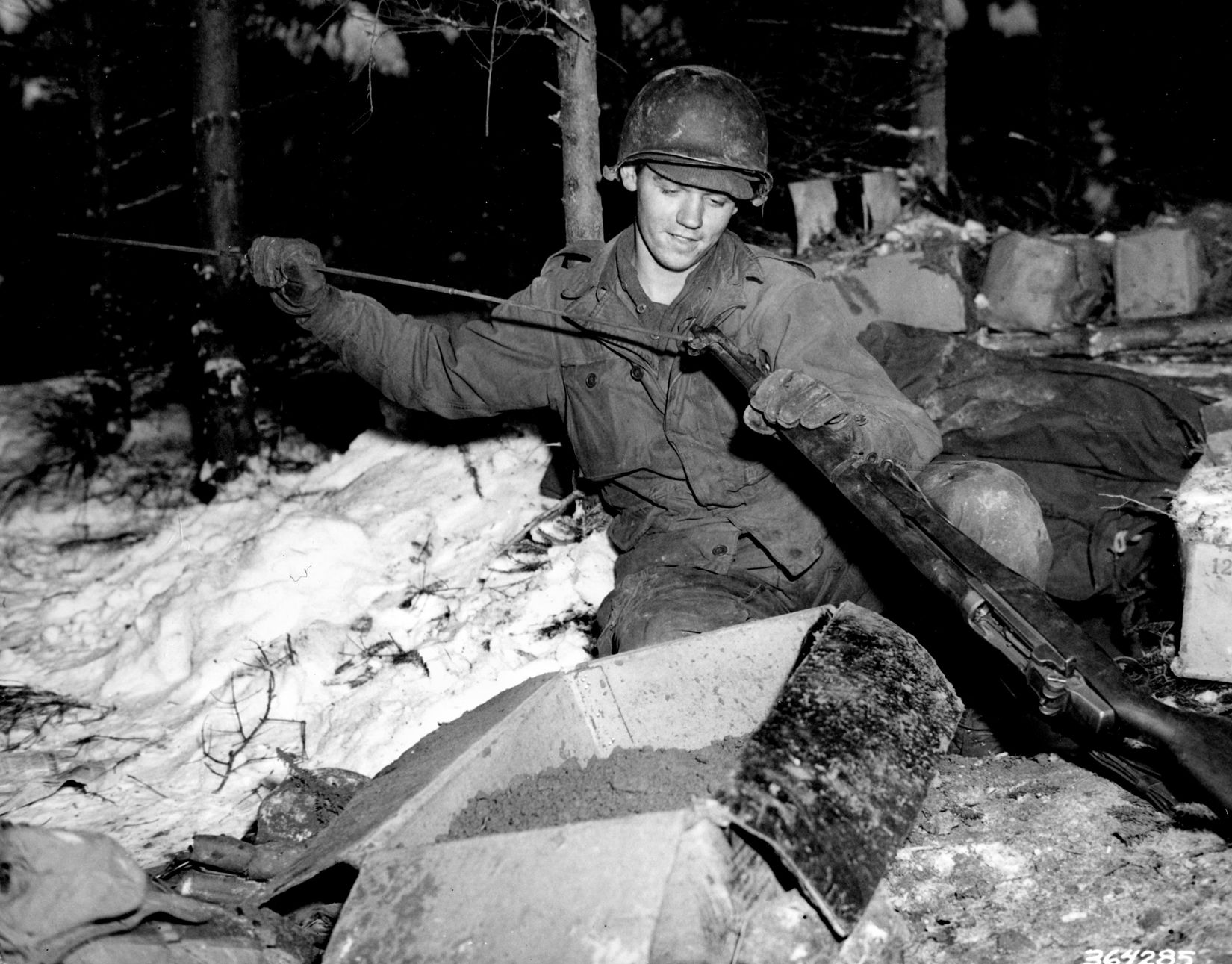 Surrounded by snow, Private First Class William Ottersbach of the 101st cleans his rifle near Foy, Belgium, January 11, 1945.
