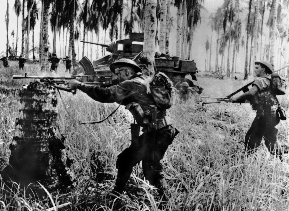 During the final push for Buna, two Australians armed with Bren guns and supported by a Stuart light tank advance toward the enemy.