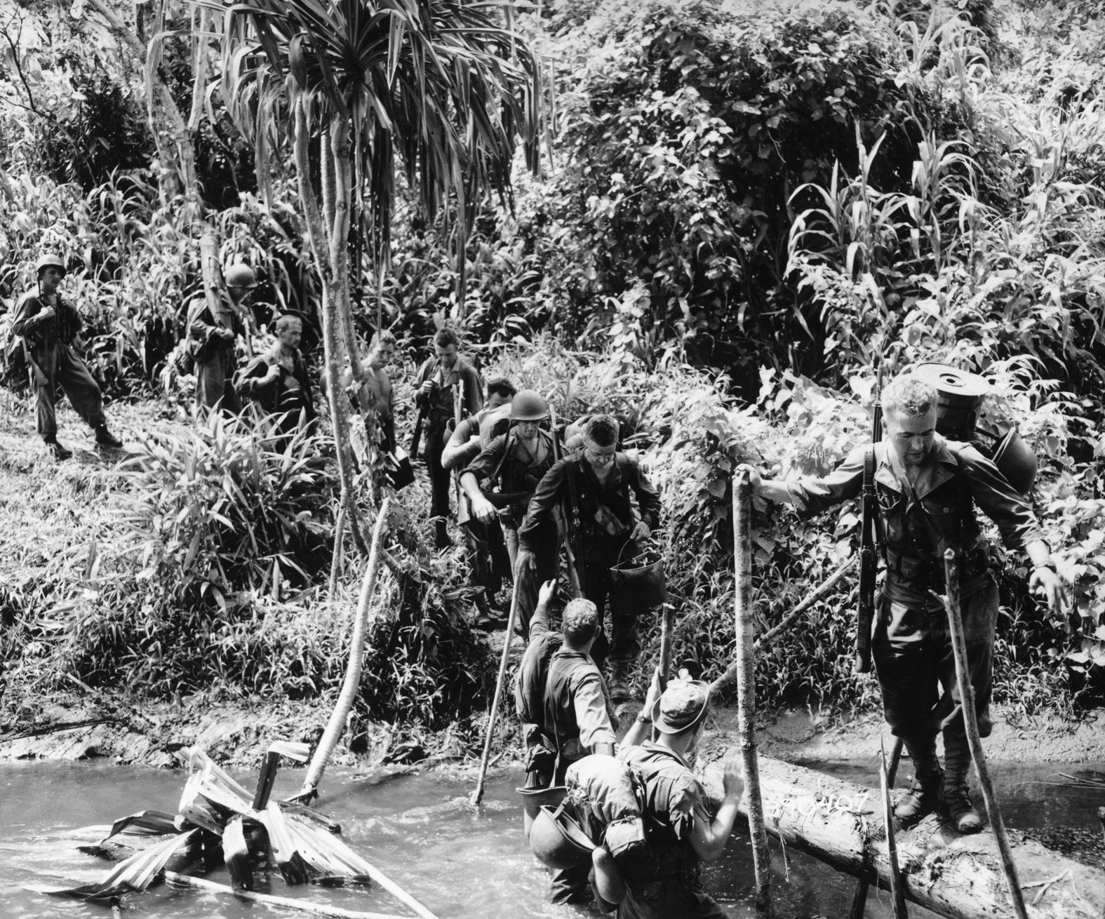 Men of Cannon Company, 128th Infantry Regiment, 32nd Division cross a branch of Kroro Creek in New Guinea on their way to Embogu, November 5, 1942.