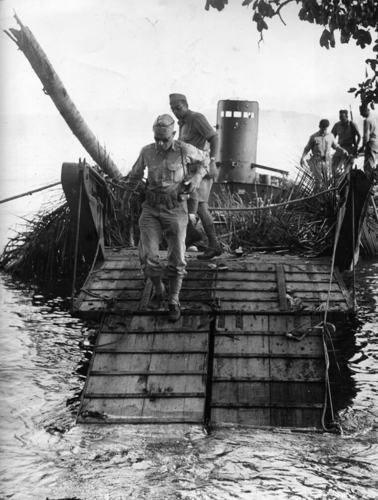American soldiers look over a Japanese barge. The enemy raiding party got ashore but was quickly wiped out by Allied marksmen. 