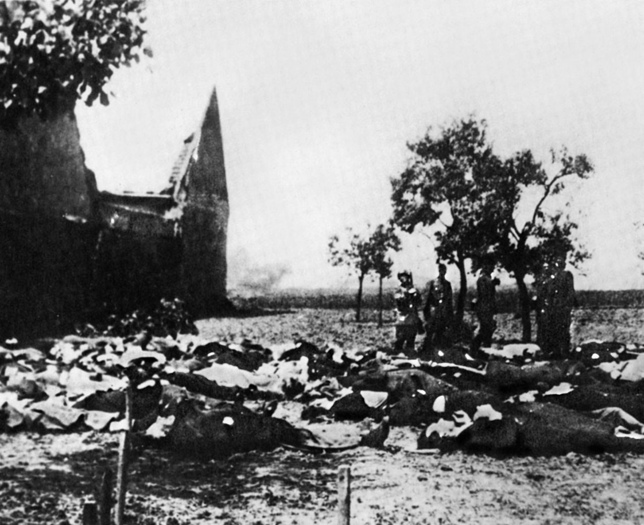 SS guards stand over the corpses of 172 men and boys of the village of Lidice, massacred in retaliation for the assassination of Heydrich.