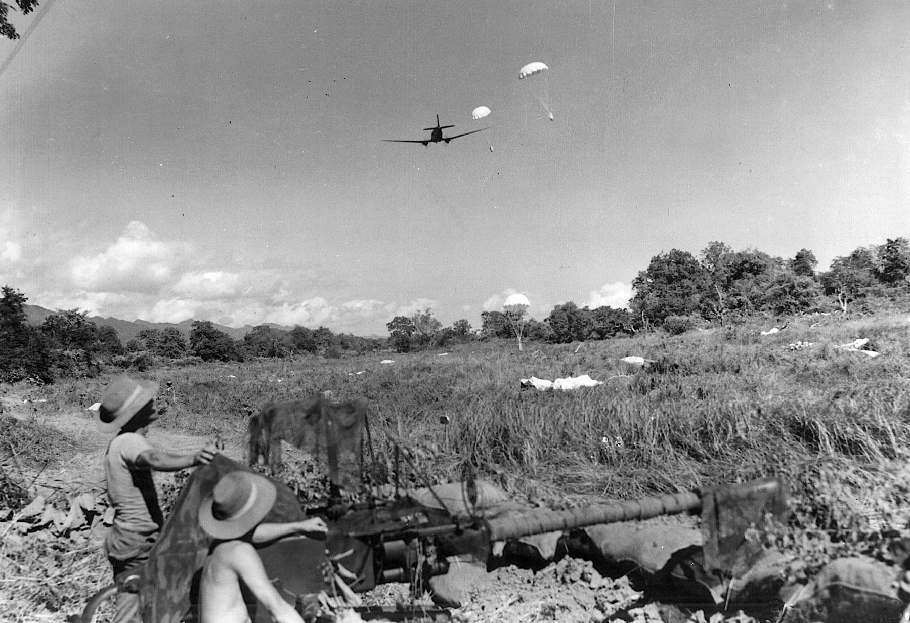 British soldiers manning a field gun watch as a C-47 drops supplies in Burma. 