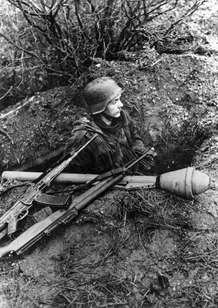 On the alert for advancing Allied troops, a German soldier appears ready to contest every inch of ground in the Vosges Mountains of France. Note the panzerfaust antitank weapon, the Mauser rifle, and the automatic weapon adjacent to his position.