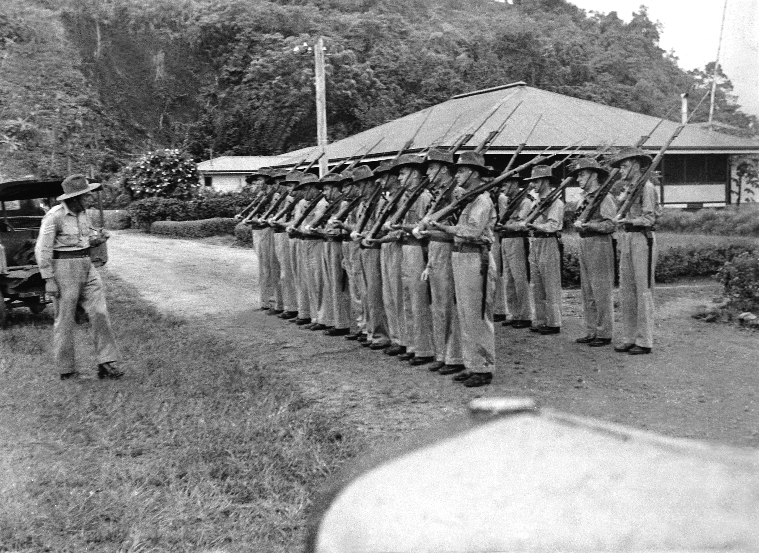 On April 25, 1940, the assembled Salamaua Platoon of the New Guinea Volunteer Rifles is drilled by its sergeant, a noncommissioned officer named Rogers.