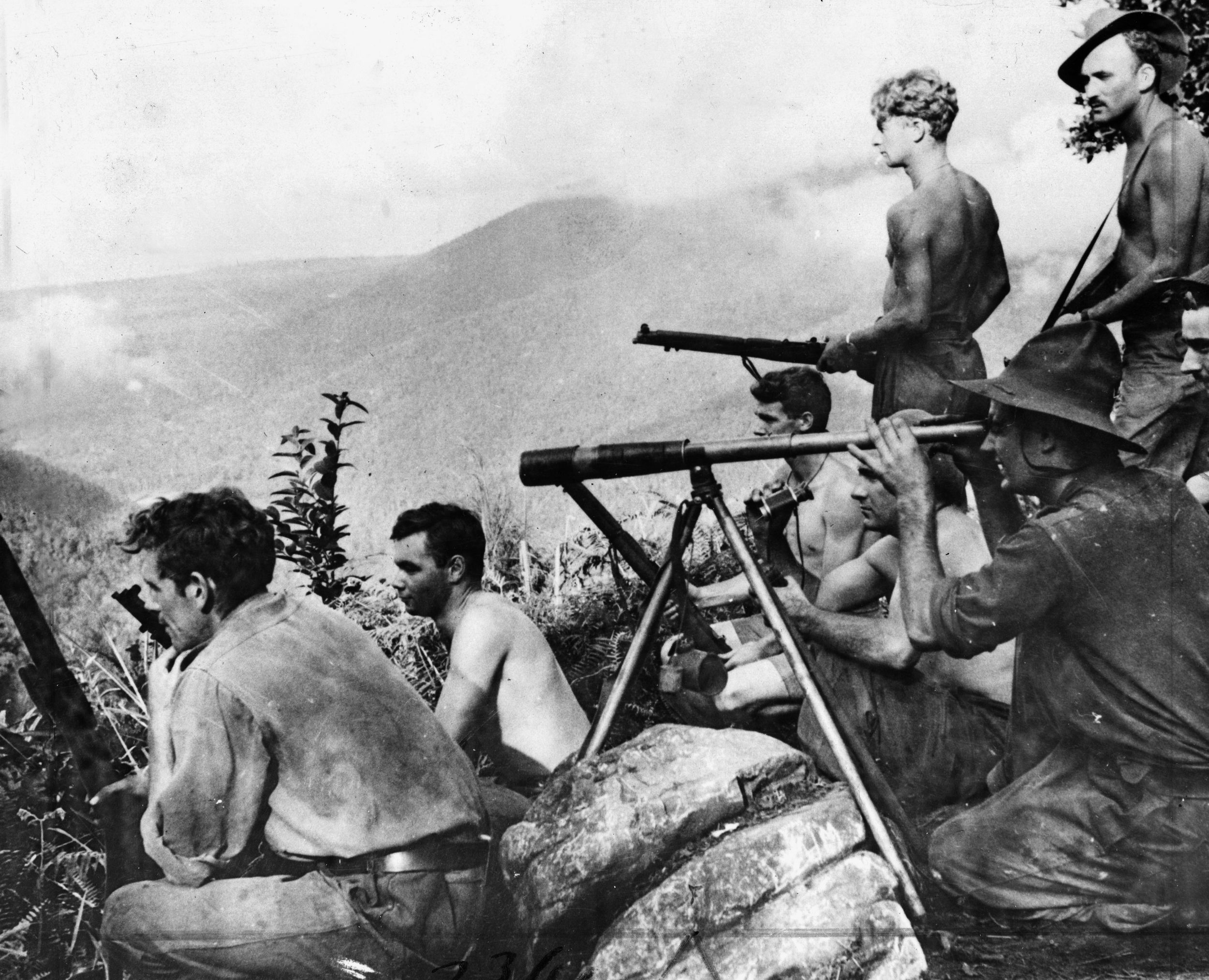  Using a telescope to view Japanese troop movements, men of the New Guinea Volunteer Rifles maintain a lookout position high in the mountains of the large island. 