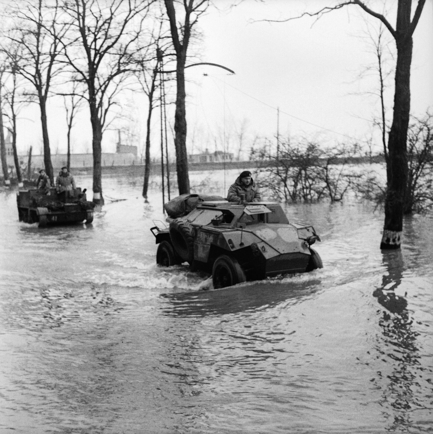 The progress of British armored vehicles was impeded when the Germans flooded low-lying areas. A British Humber scout car and a universal carrier are shown crossing a flooded road between the towns of Beek and Kranenburg.