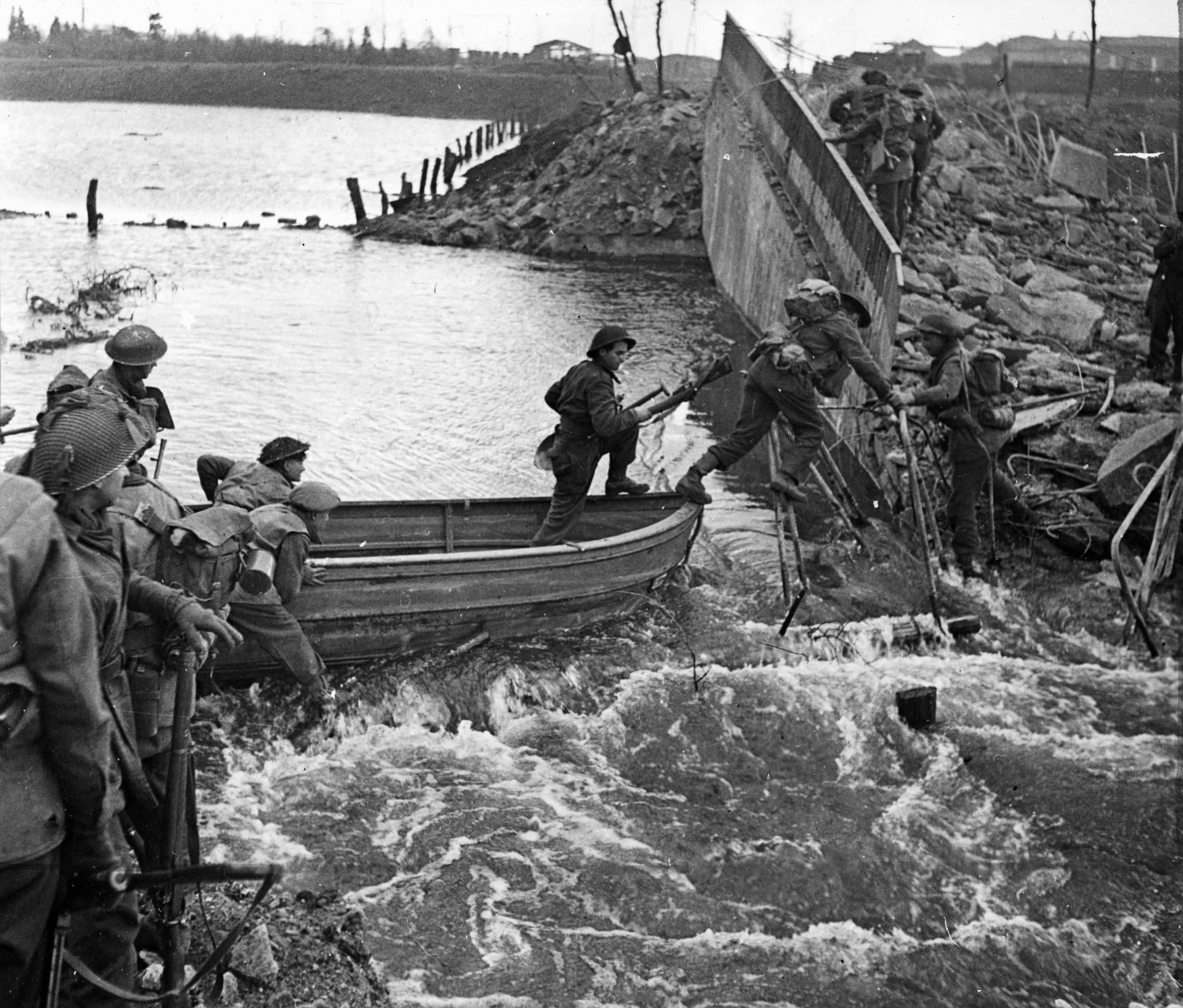 After crossing the Niers River on March 2, 1945, British soldiers exit their small boats and scramble up the riverbank. Their objective was the nearby town of Weeze.
