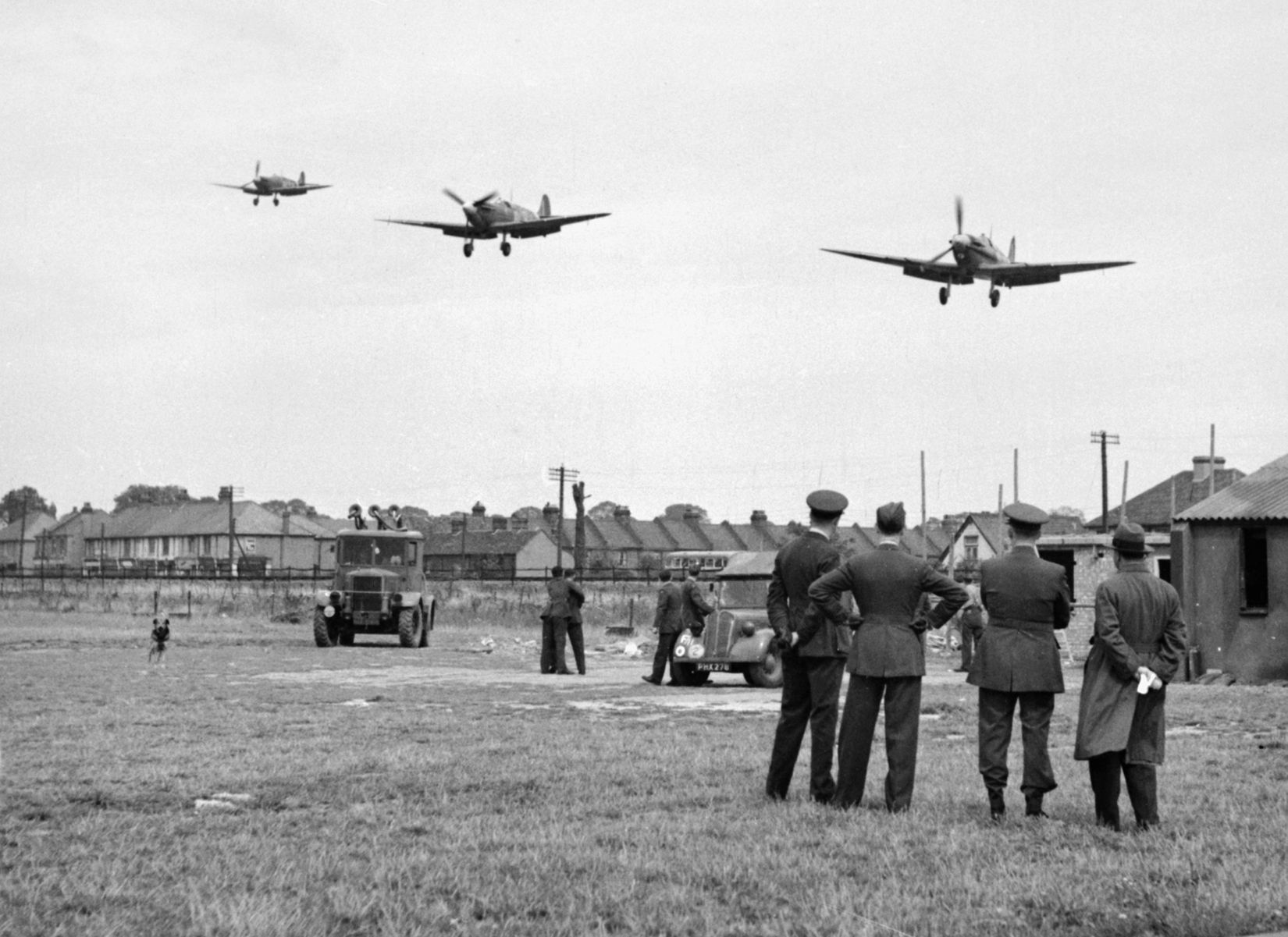 Members of 121 Squadron watch as three of their comrades return to their base at RAF North Weald after a sweep over northern France, August 1942.