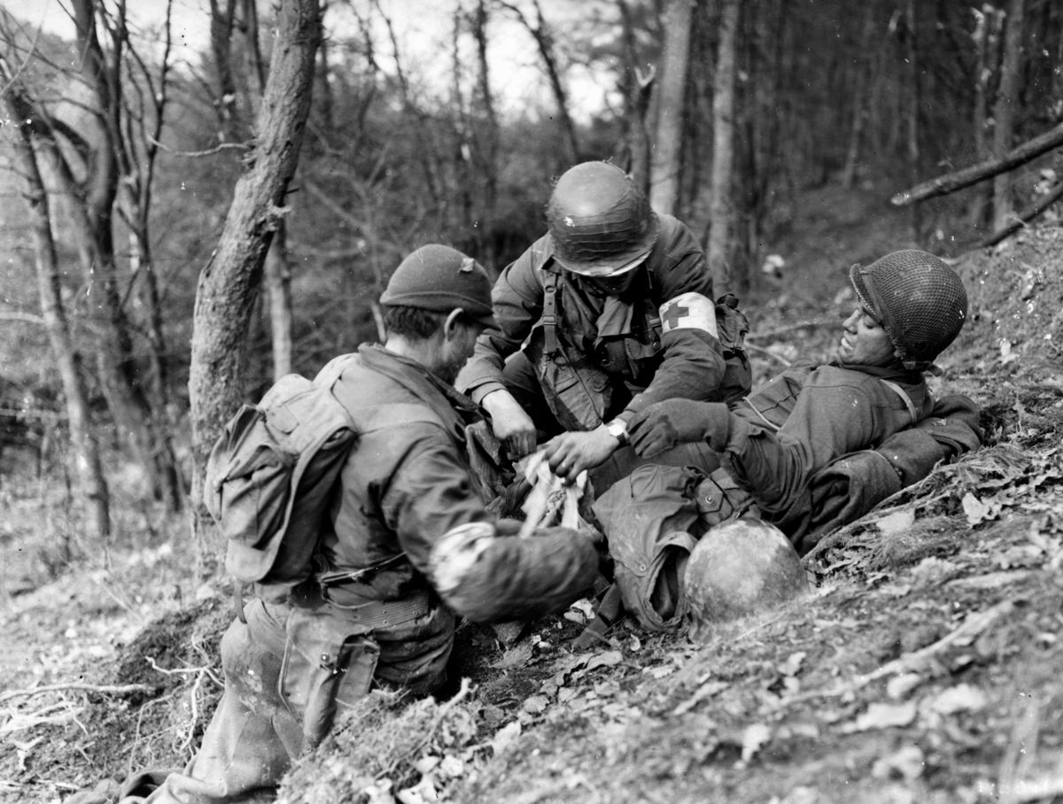 Two medics of Company I, 3rd Battalion, 8th Regiment, 4th Infantry Division treat a wounded infantryman in the Hürtgen Forest near Düren, November 18, 1944.