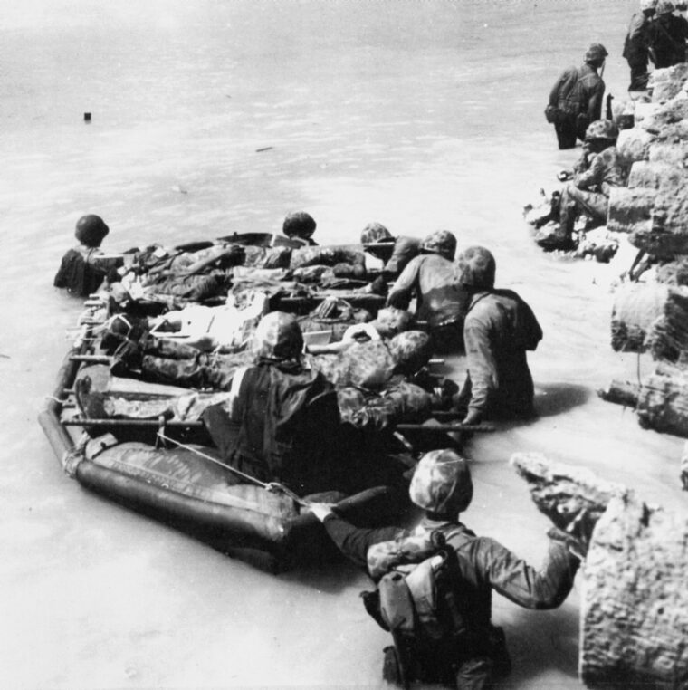 With amtracs in short supply the day after the landing, wounded Marines are transported from the pier on a rubber assault boat to the reef, where landing craft, such as Larry Wade’s, would take them to nearby ships.
