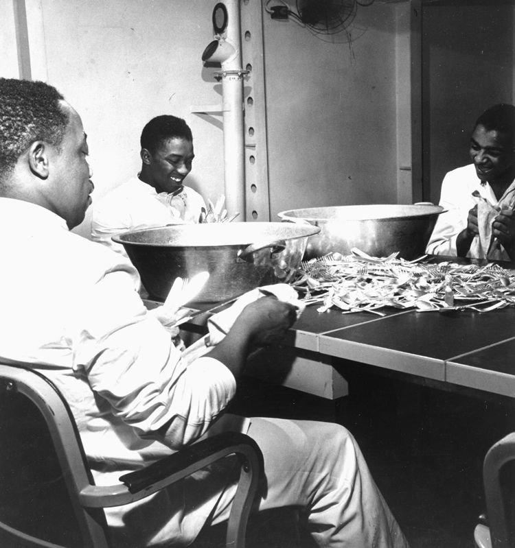 Steward’s Mates joke as they dry silverware in the wardroom of the USS Ticonderoga, November 1944.