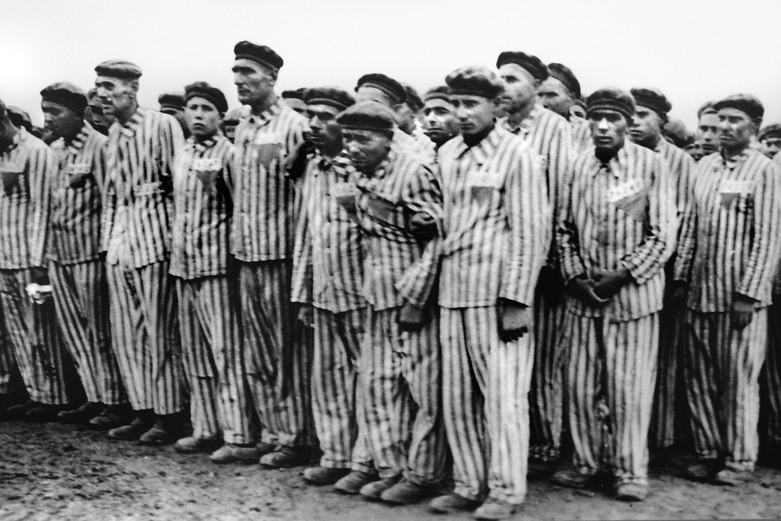 Concentration camp inmates lined up for a work detail wear identifying colored triangles on their prison uniforms. The triangles were used as a means of identifying each inmate’s category of prisoner.