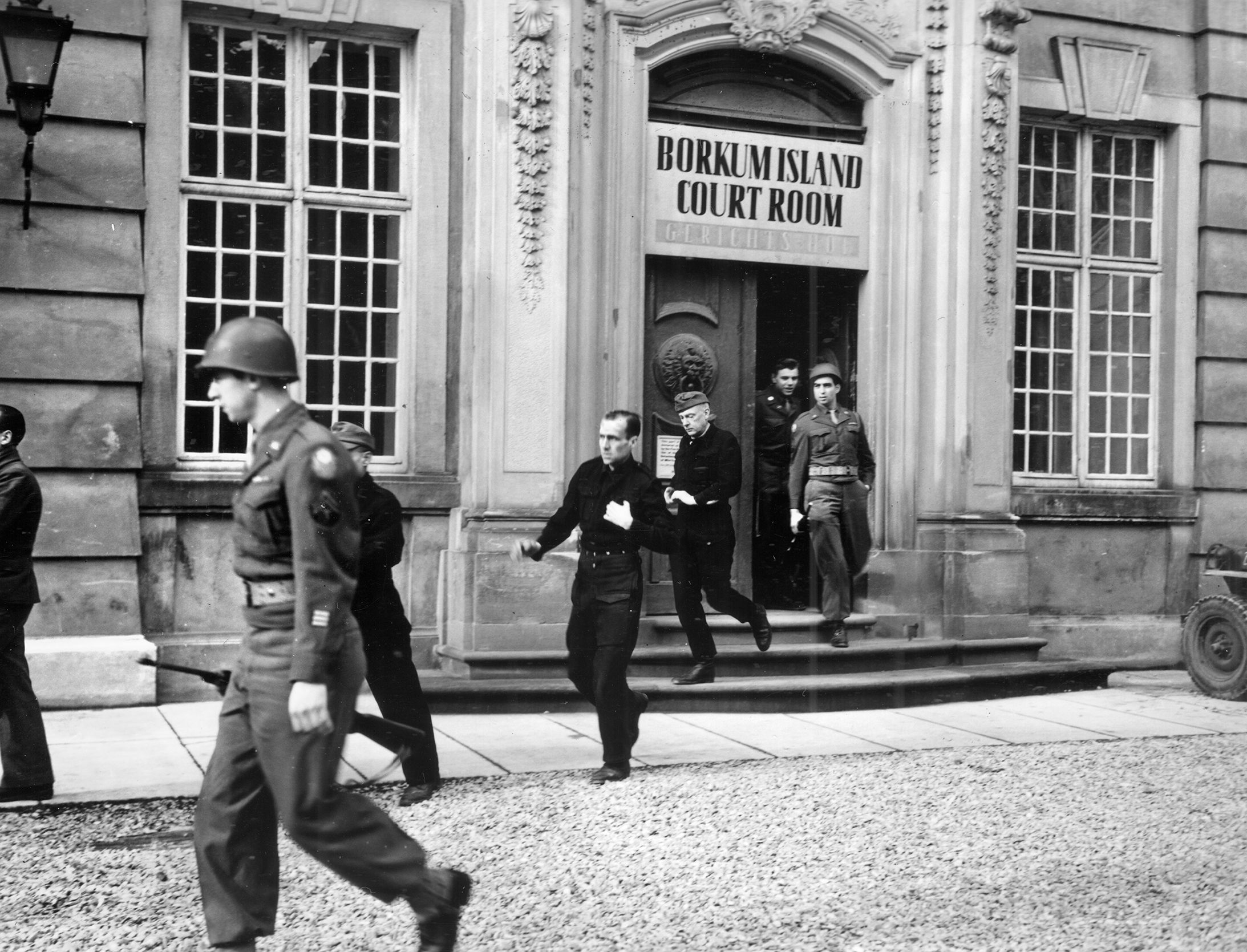In February 1946, defendants leave the court room during the war crimes trial held at Borkum Island. The accused were convicted and some had their sentences reduced. 