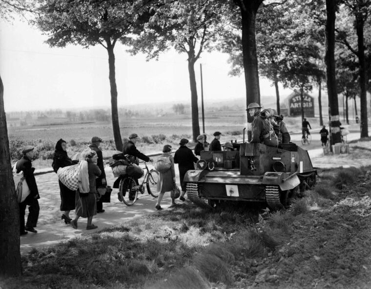 A British Bren gun carrier passes a long line of French refugees fleeing the onslaught of the German Army in the spring of 1940. The British soldiers are headed toward the Belgian frontier in the forlorn attempt to stem the German tide.