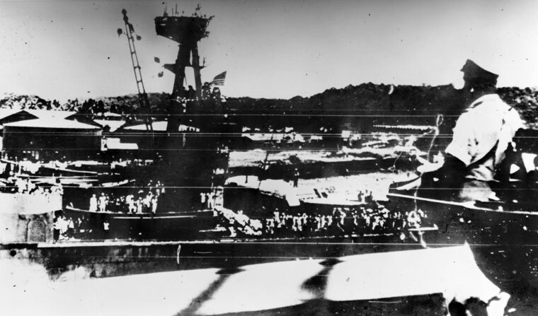 In the photo taken from the deck of the cruiser USS Marblehead, the flag of the Houston flies at half-mast for two crewmen killed when a Japanese bomb struck near an eight-inch gun turret in earlier action.