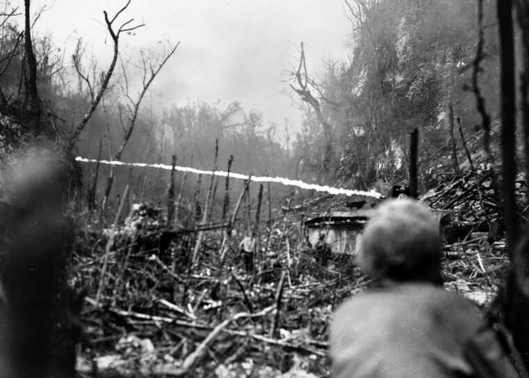 Marines watch as a flame-throwing amphibious tractor fires at caves in the mountainous areas used by the Japanese during the fight for the Pacific island of Peleliu. The lowlands and the airport were quickly captured, but the Umurbrogol massif—a series of limestone and choral ridges rising as high as 300 feet took much longer. A moonscape of sinkholes, canyons and cliffs further fortified by Japanese engineers, the “Umurbrogal Pocket,” and the island, was finally declared secure 73 days after the Marines had landed.
