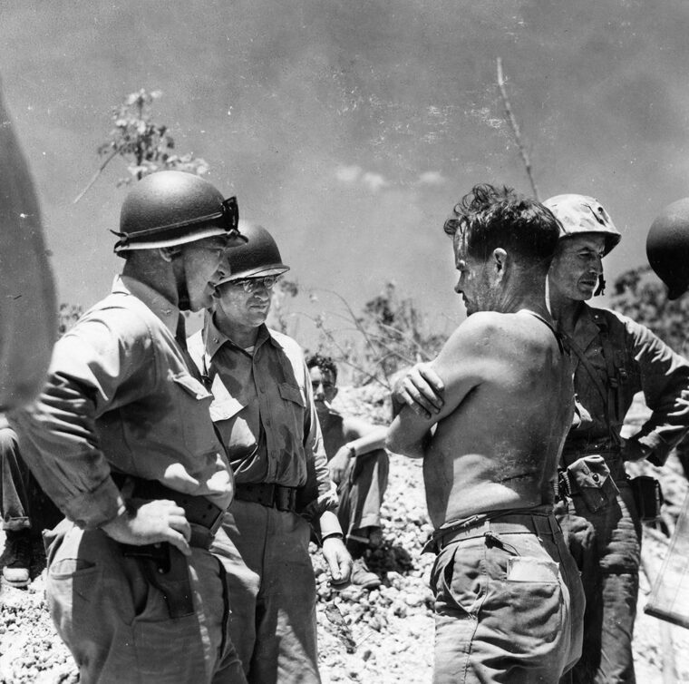 Lieutenant Colonel “Chesty” Puller, shirtless, discusses the the situation in the rugged and fortified highlands with Admiral Edward Cochrane on Peleliu. 