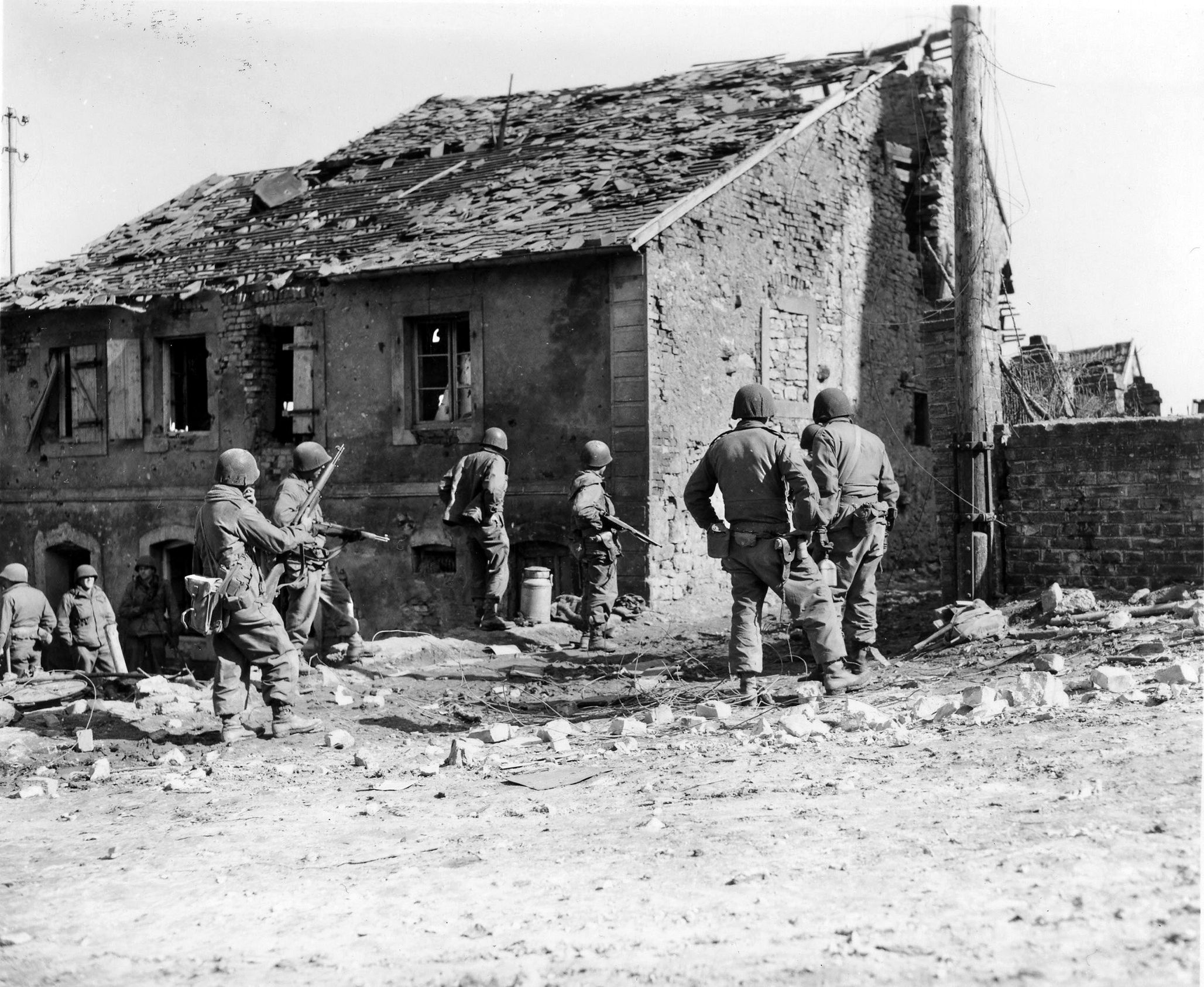 Soldiers of the 7th Infantry Regiment surround a house near Guiderkirch, in the Alsace-Lorraine region of France, where German snipers are holed up, March 1945.