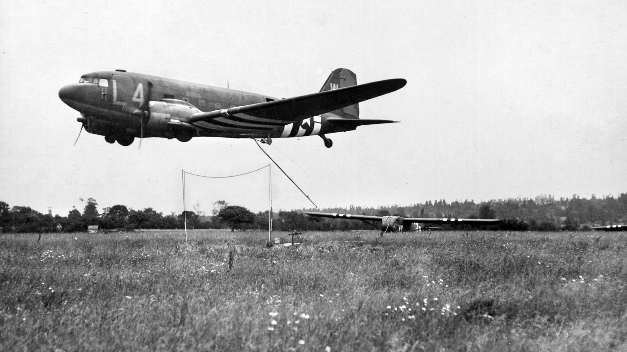 Due to the high attrition rate, very few gliders could be reused. Here, in what is called a “snap take-off,” a C-47 attempts to hook the tow rope of a CG-4A and retrieve it from a field in Normandy. 