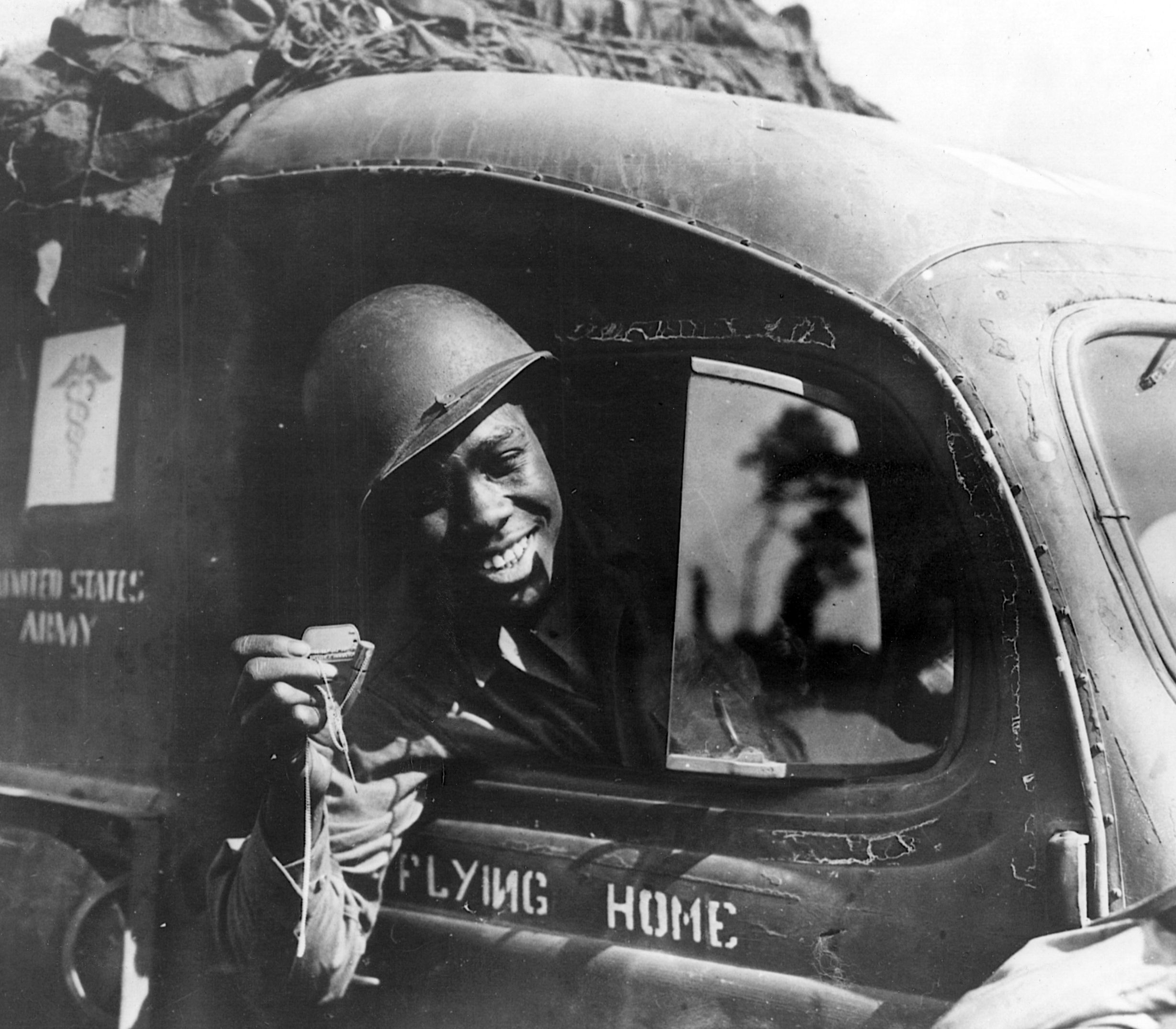 A GI ambulance driver shows a .50-caliber bullet attached to his dogtags. The bullet, shot from a strafing German fighter, imbedded itself in his windshield. 