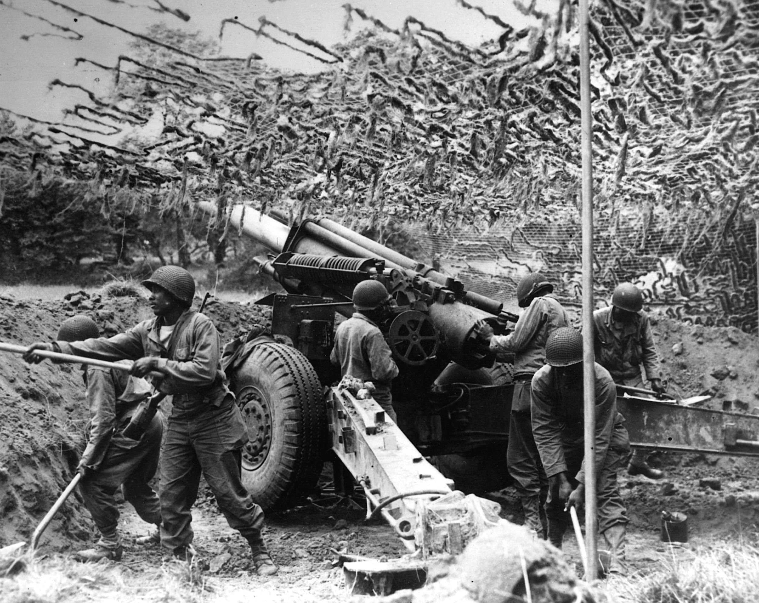 An Army artillery crew keeps fire on German defenses in France during the Normandy campaign. 