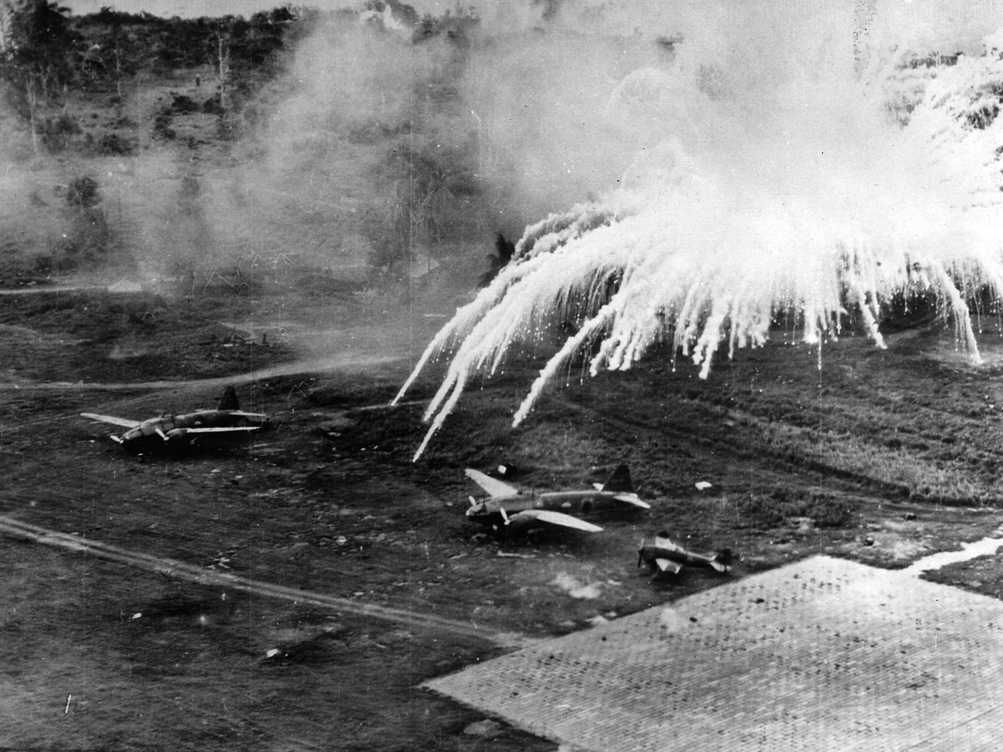 Explosions rock a Japanese air field near Rabaul. American B-25s and P-38s from the Fifth Air Force hammered the site unmercifully.